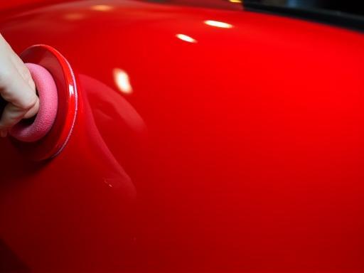 Red car panel being polished